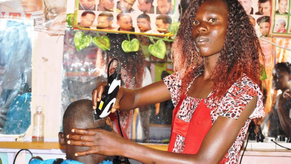  Mildred Wanjala attends to a customer at her Bungoma County barbershop
