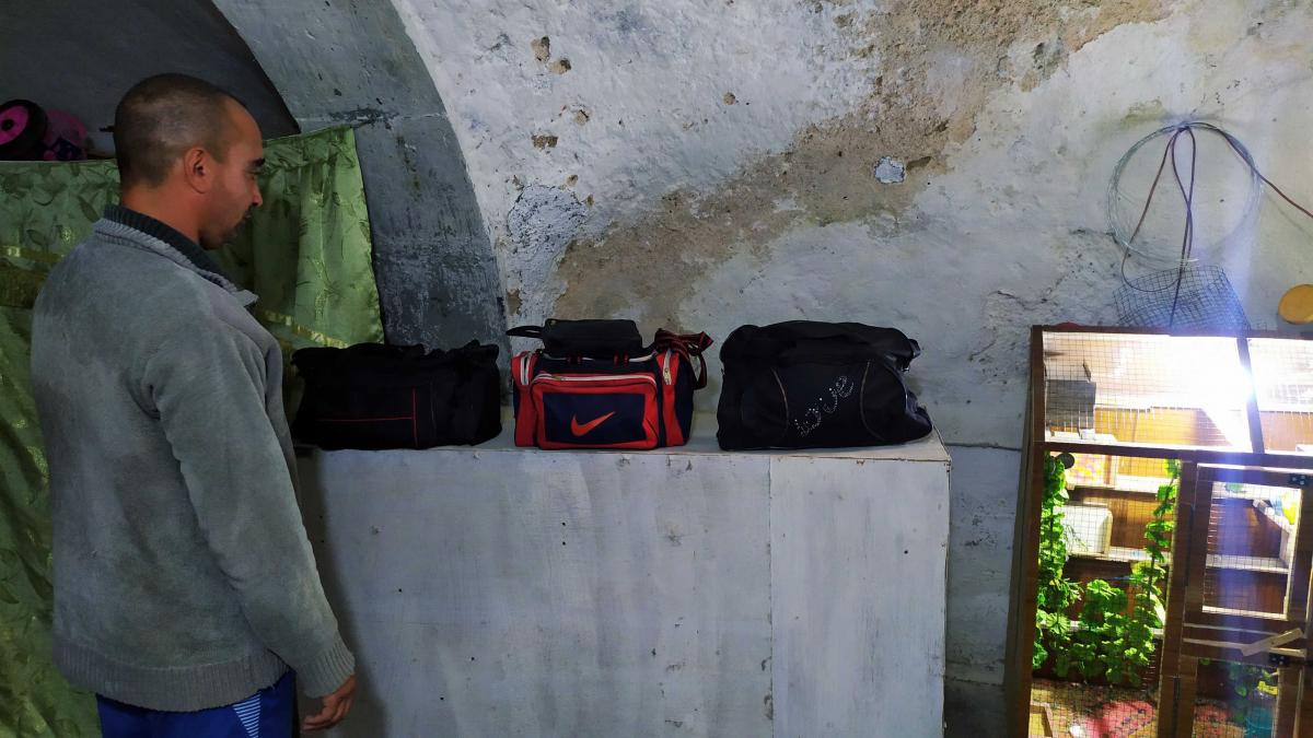 Ahmed stands next to bags he repaired. He dreams of one day having his own shop and tools to develop his own brand of bags, "made in Mosul".