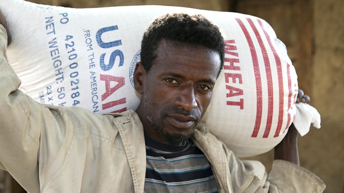A man carries a bag of wheat from USAID