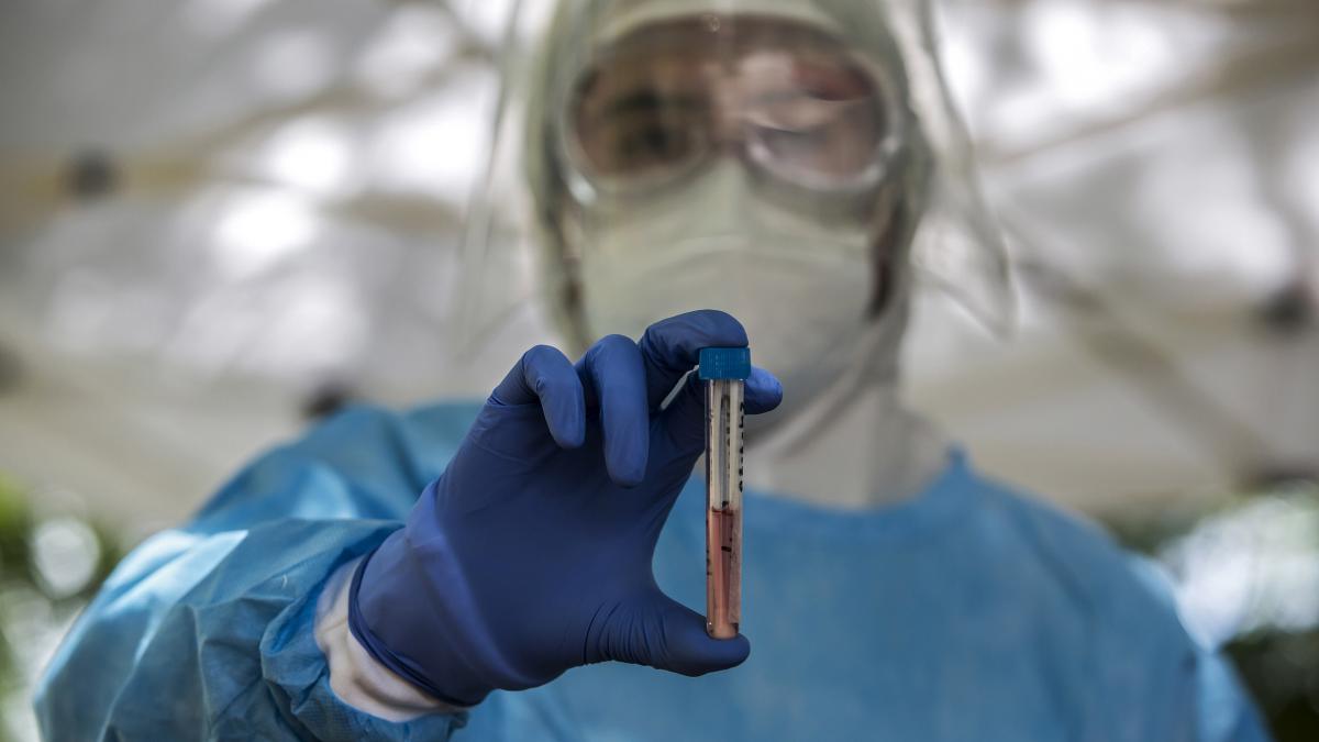 healthcare worker holding a test tube in PPE 