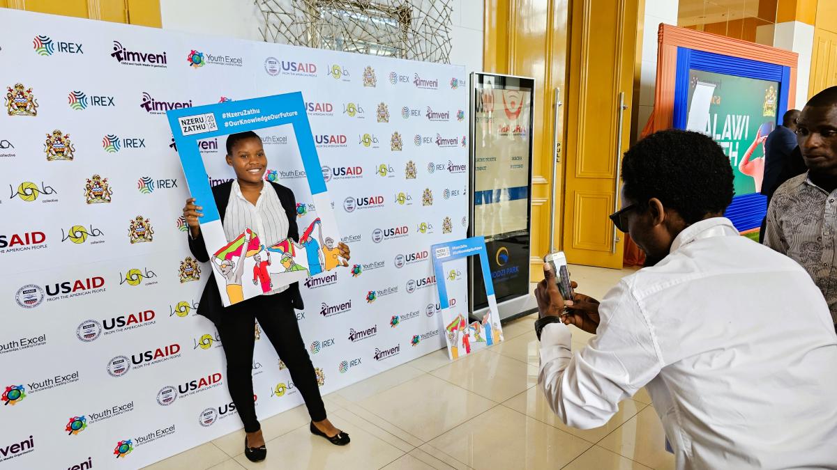 One of the participants in the Nzeru Zathu "Our Knowledge" Youth Summit poses for a photo in the open gallery outside the event hall. Photo: Oris Chimenya/USAID