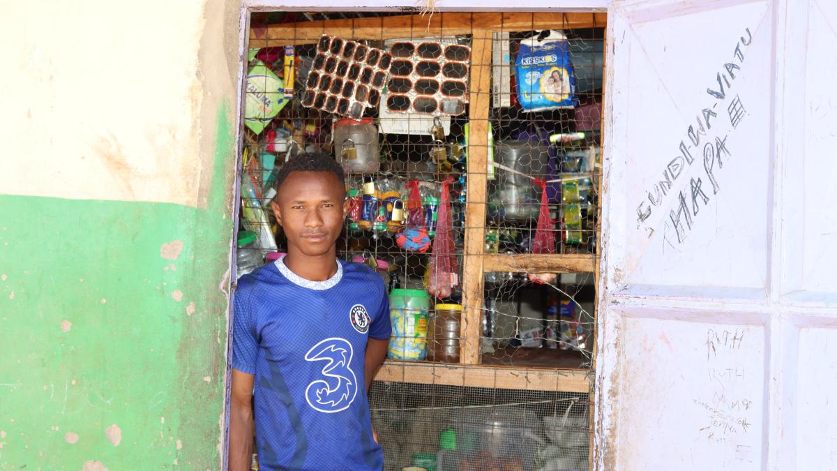James Lordo stands outside his retail shop as he waits for customers. Photo credit: Saruni Letiwa/USAID