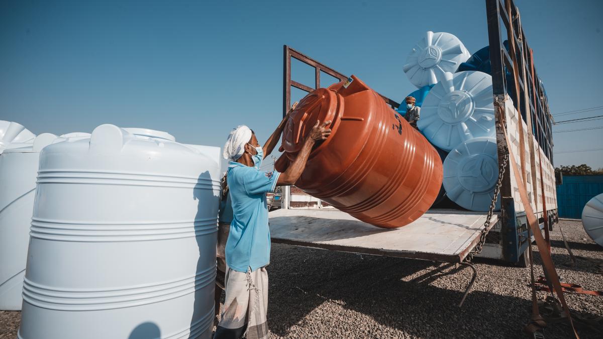 A worker lifts a plastic water tank at the USAID-supported Al Harmeen Factory in Lahij Governorate, Yemen.