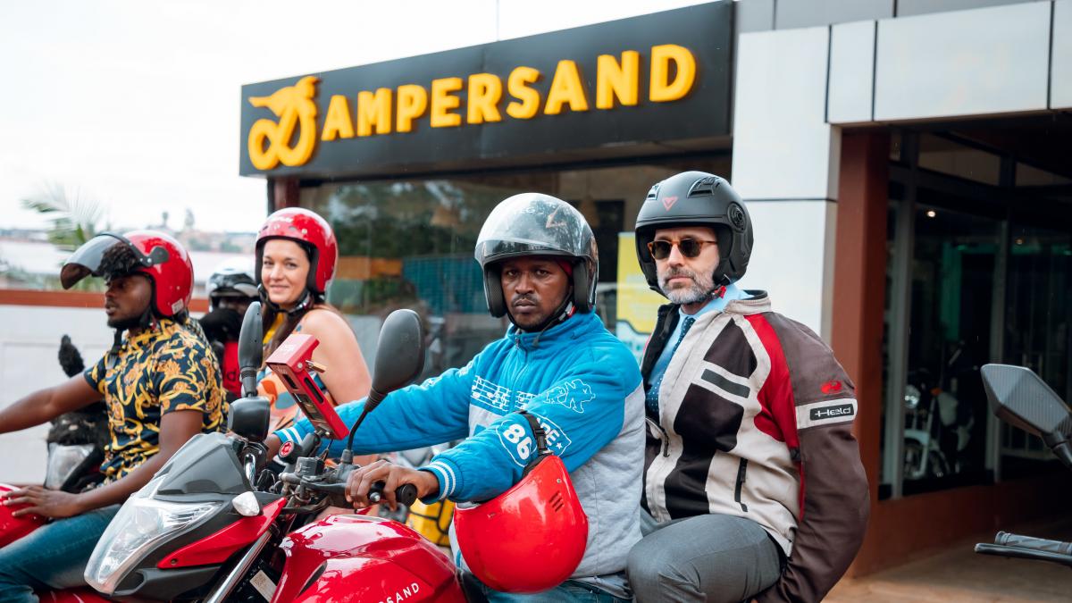 Power Africa staff sitting on e-bikes in front of the Ampersand office