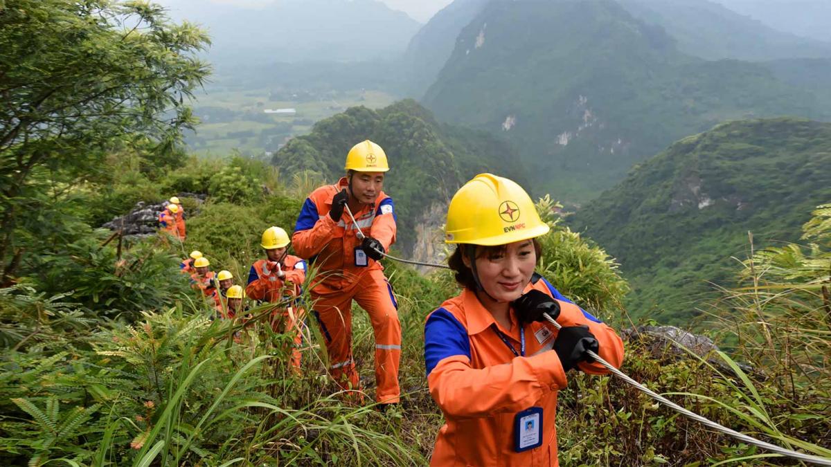 Female and male utility workers lay power lines through a rural landscape