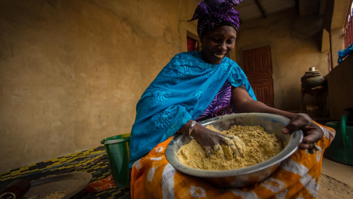 A woman sorting through grain in a large wide bowl.