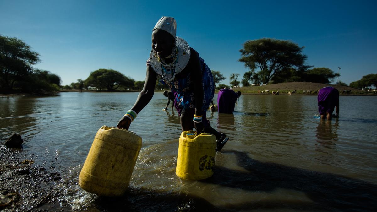 Woman in Tanzania filling up water jugs.
