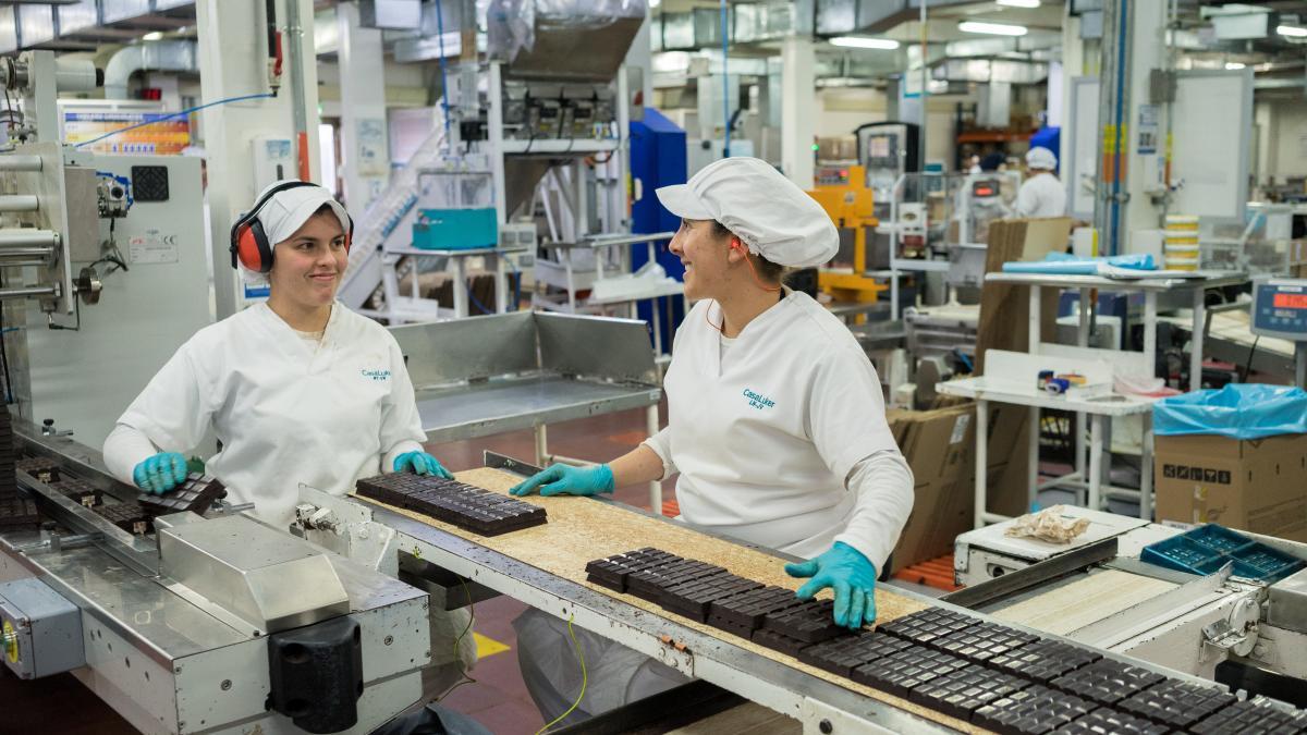 Two factory workers with chocolate on the assembly line