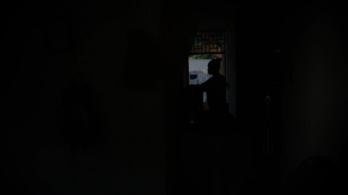 A woman is silhouetted in a dark room.