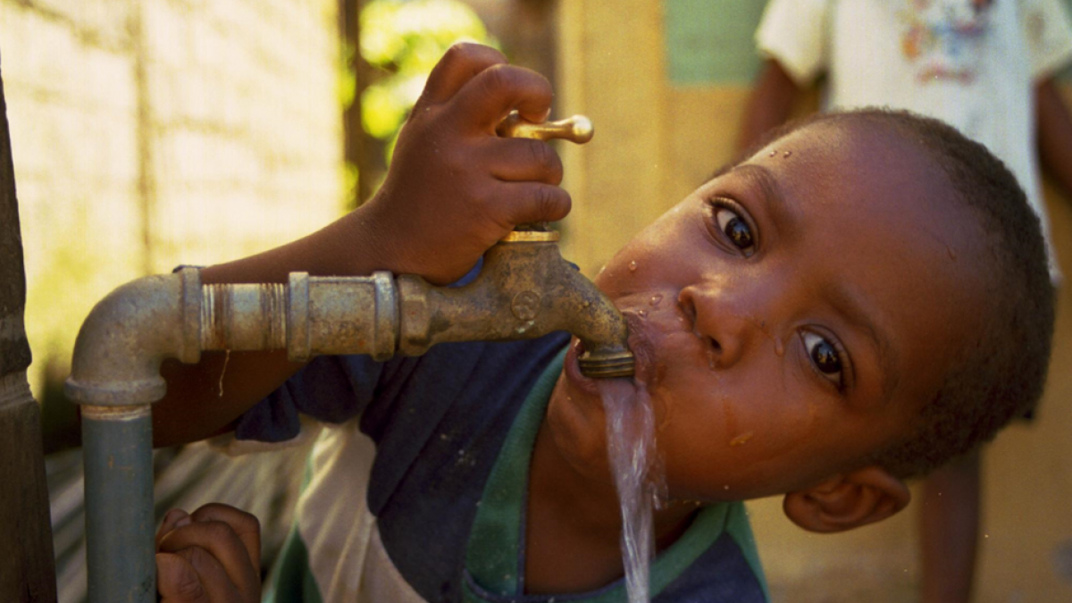A boy drinks water from the spigot