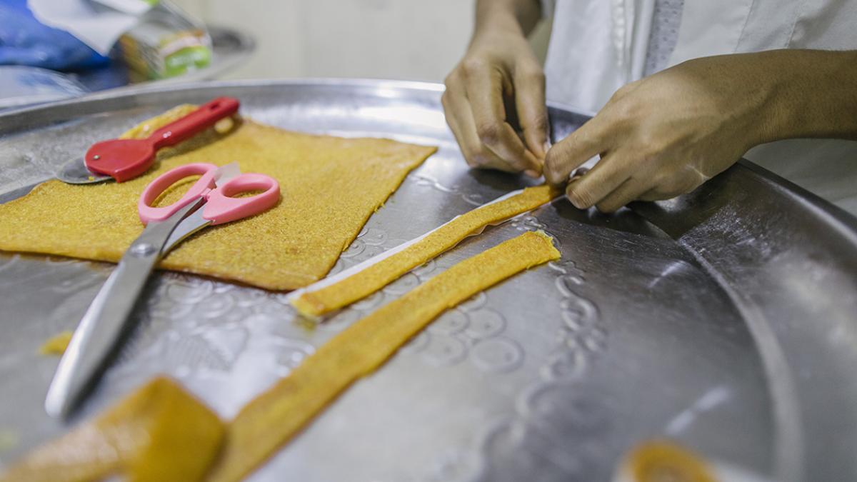 Close up of hands preparing strips of dough.