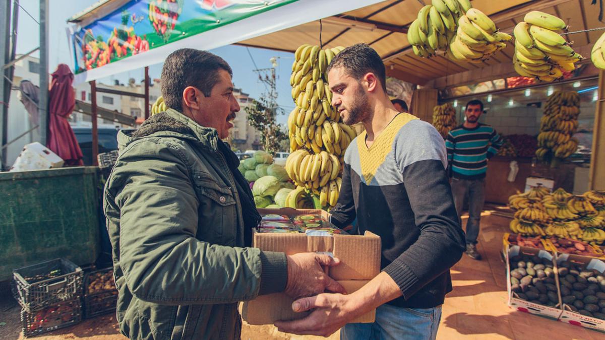 Osama Abu Al-Rub brings his fruit to the fruit shop co-owned by Jihad Al Shalabi in Jenin Governorate, Palestine. 