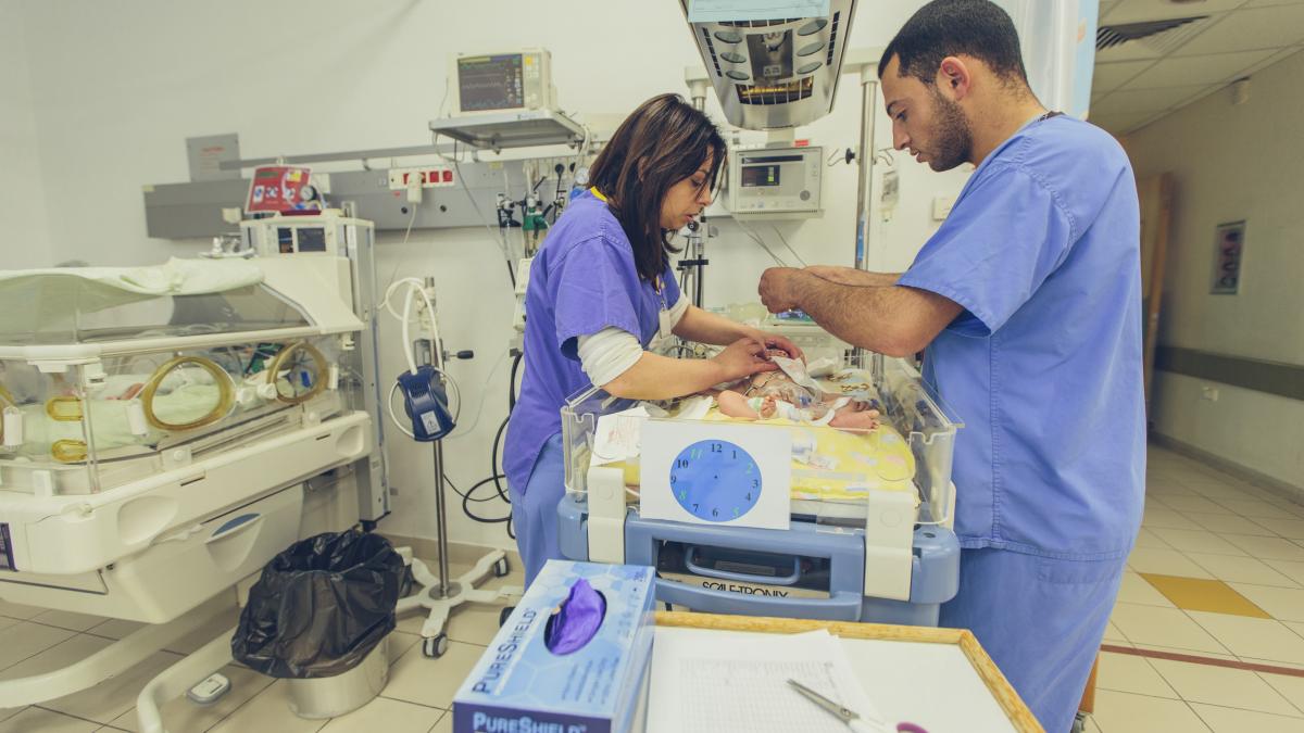 Two doctors tend to a premature baby