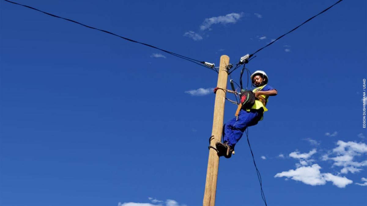 A woman technician works on a electricity pole.
