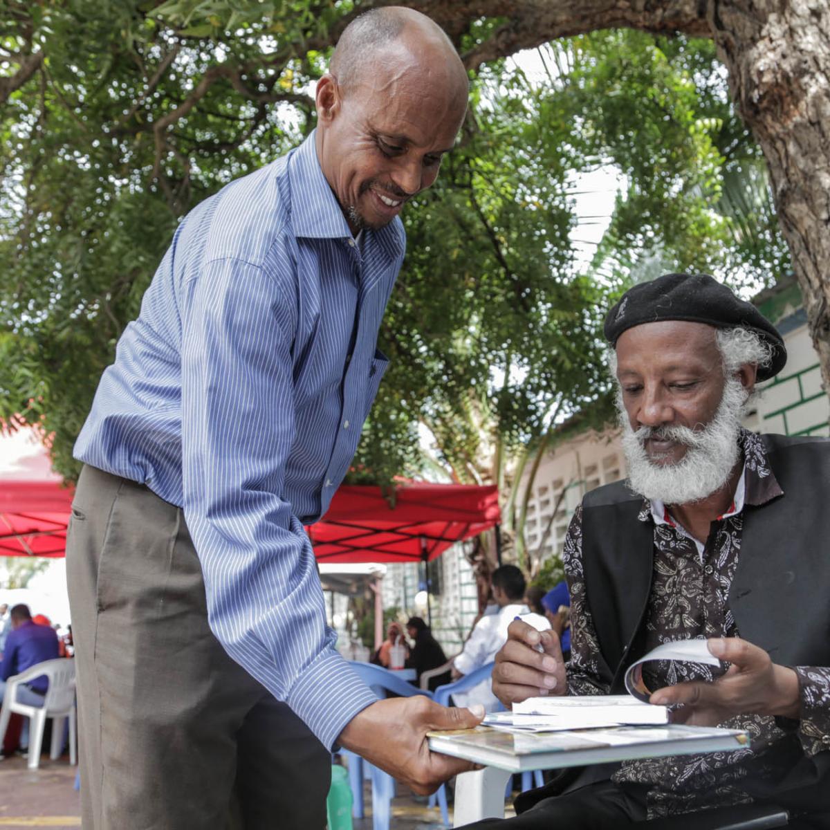 Abdilatif Ega, a renowned international author at the Mogadisihu Book Fair, signs a copy of his novel ‘Guban.’ 
