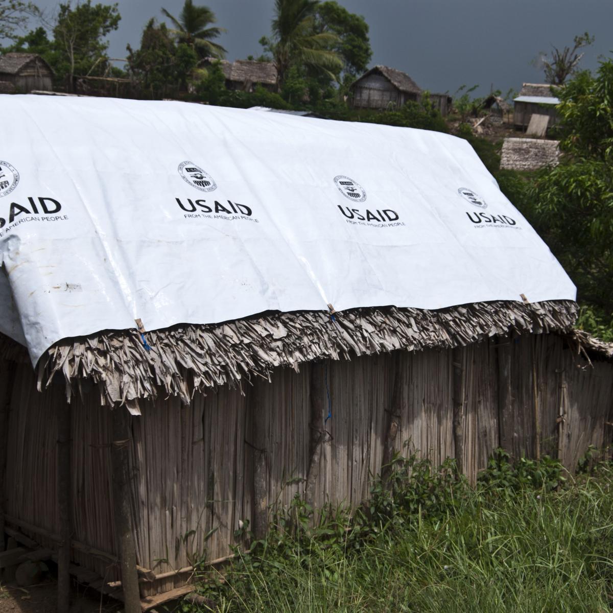 Bâche de l'USAID sur le toit d'une hutte en bois dans la campagne malgache.