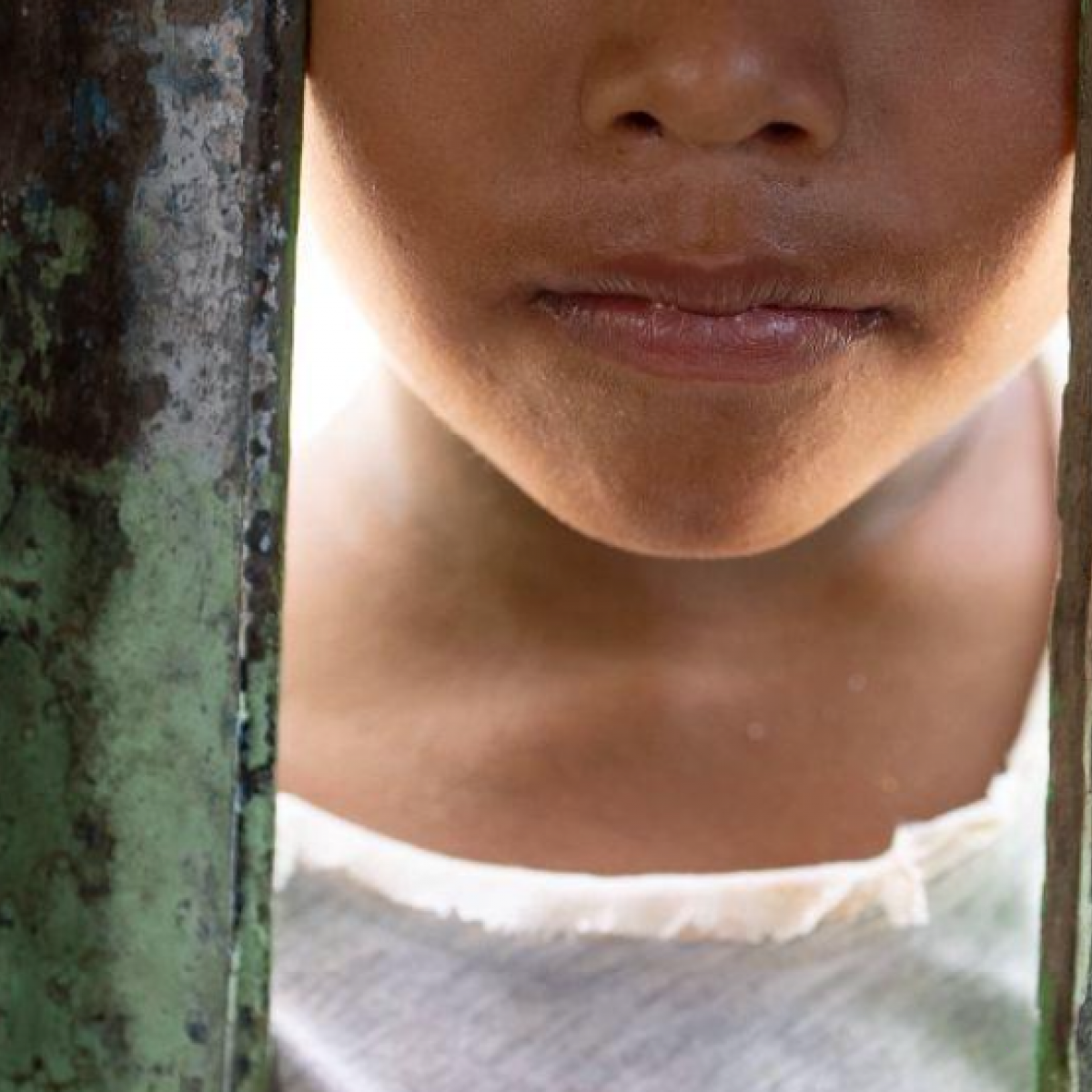 Un niño mirando a través de una pared de madera en la Amazonía