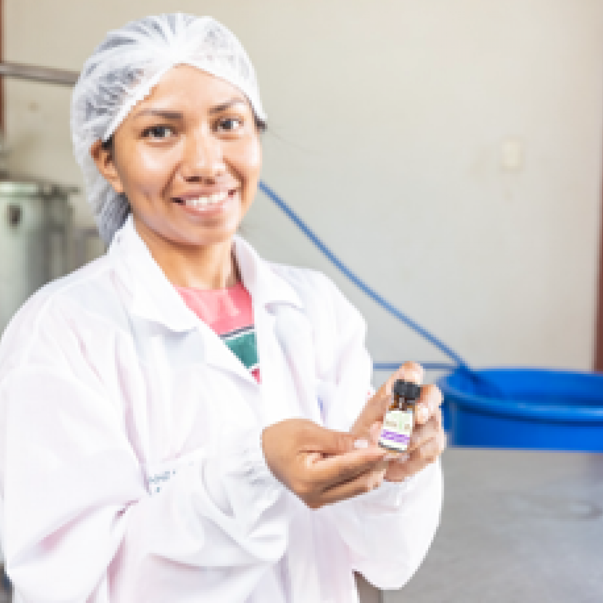 A woman dressed in a lab coat is holding a bottle of Amazonian essential oil