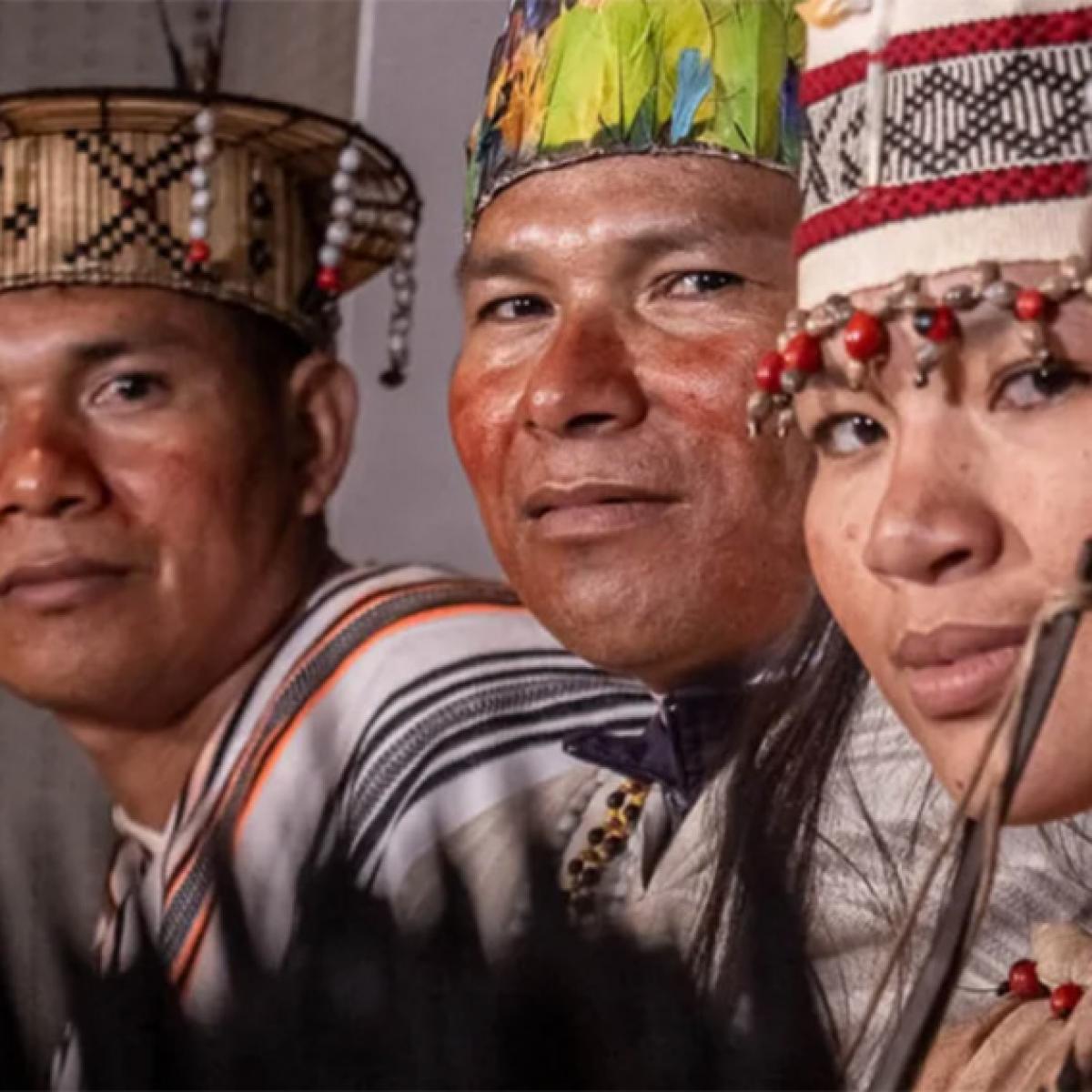 Rostros de tres personas indígenas, dos hombres y una mujer.