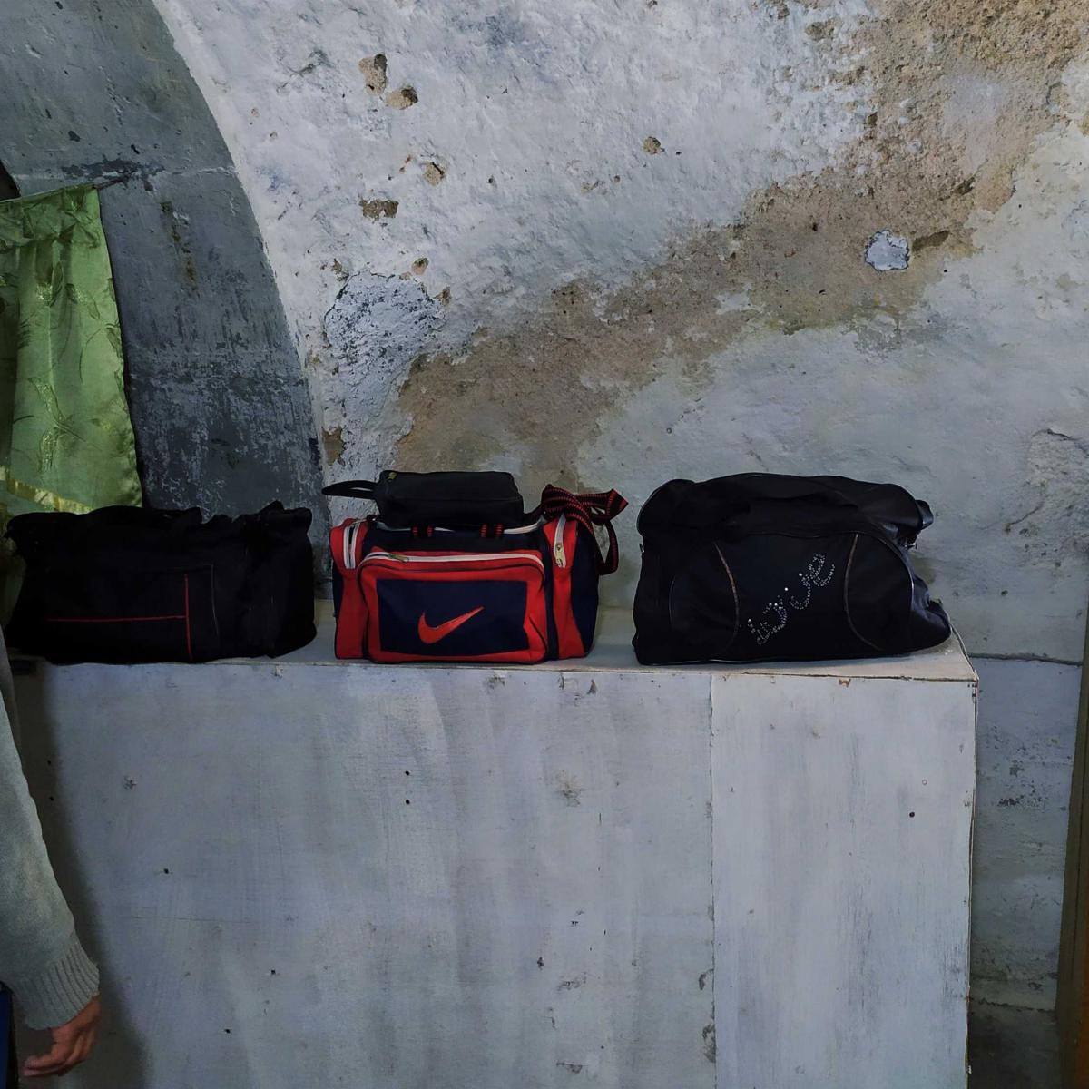 Ahmed stands next to bags he repaired. He dreams of one day having his own shop and tools to develop his own brand of bags, "made in Mosul".