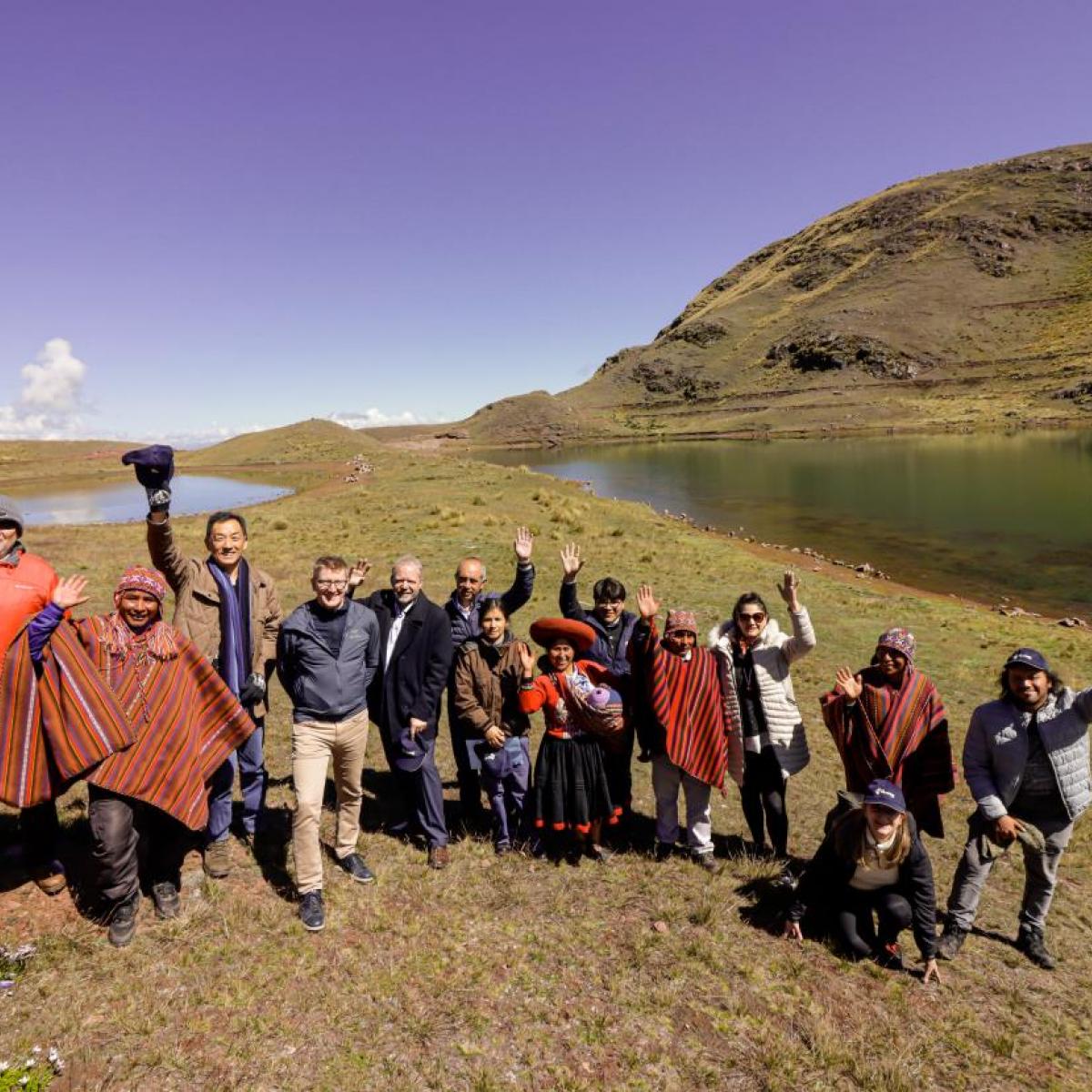 A group of people raising hands in front of an Andean wetland