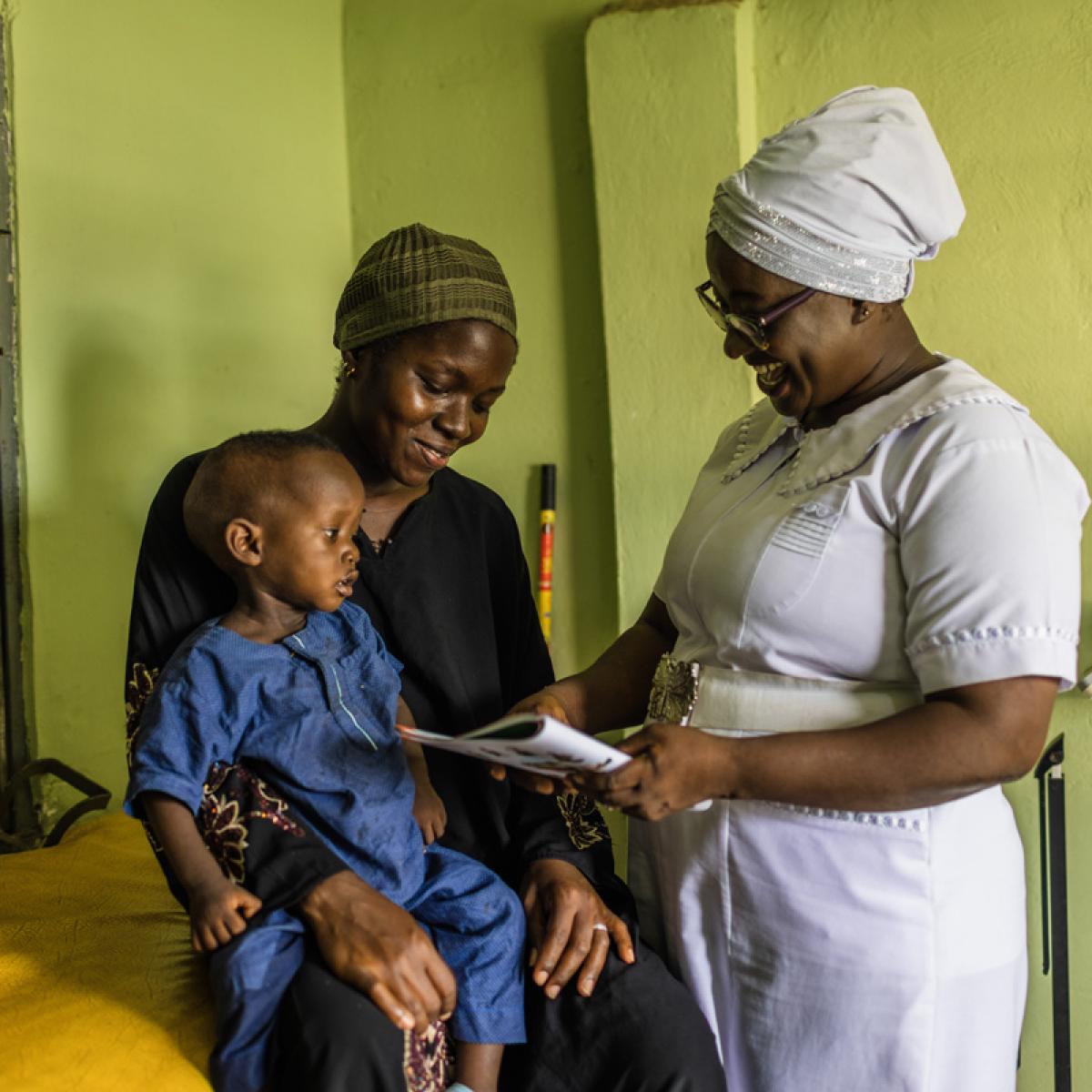 Adama, the lead midwife at Tamale Reproductive and Child Health Center in northern Ghana, shares health information with a mother and child.