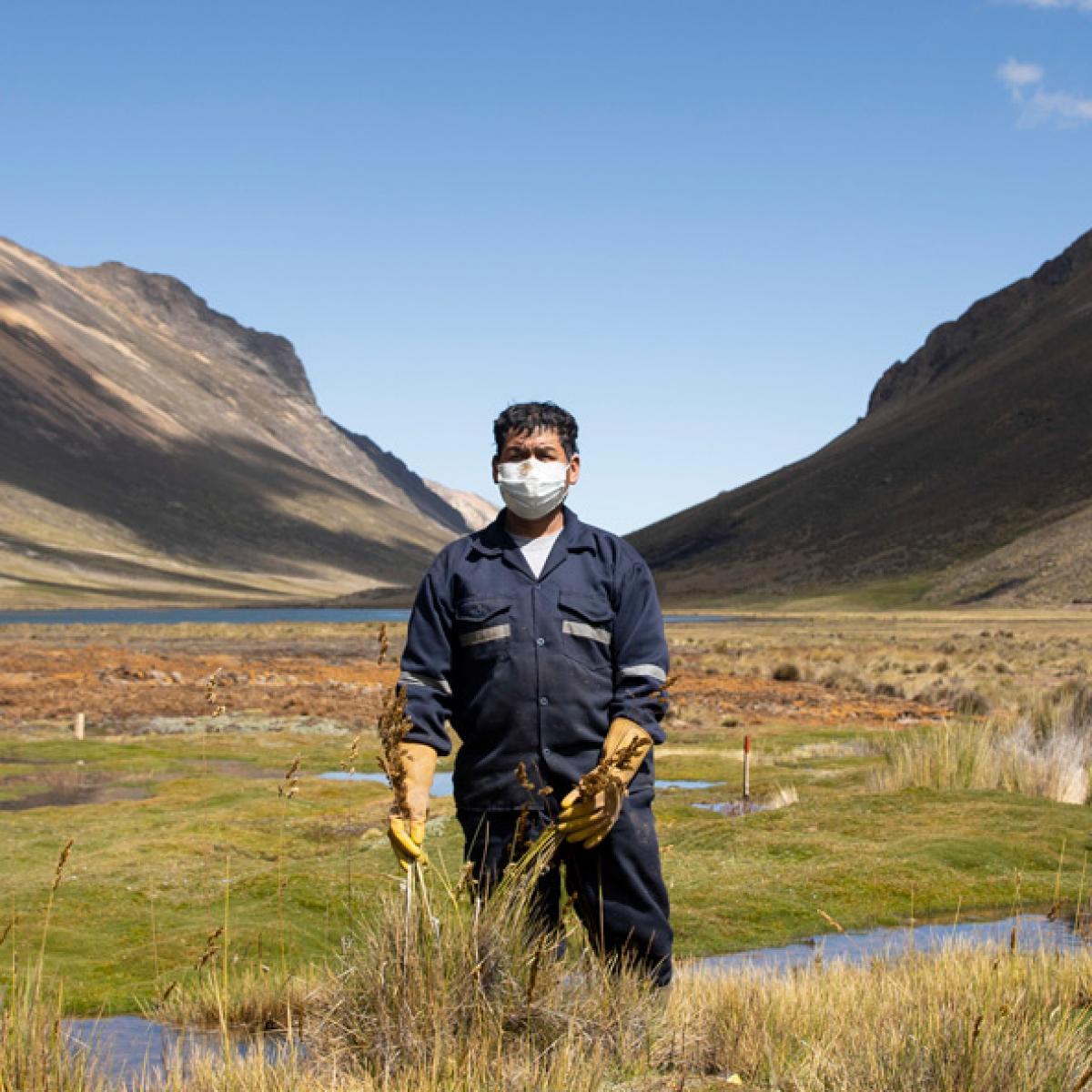 A man standing in a wetland surronded by mountains