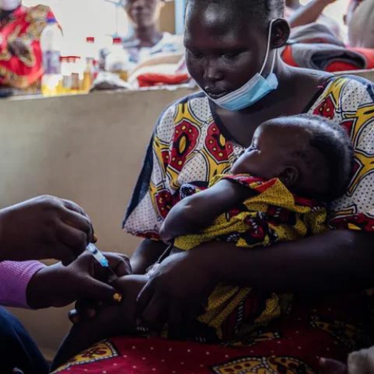 Woman holding child receiving vaccine 