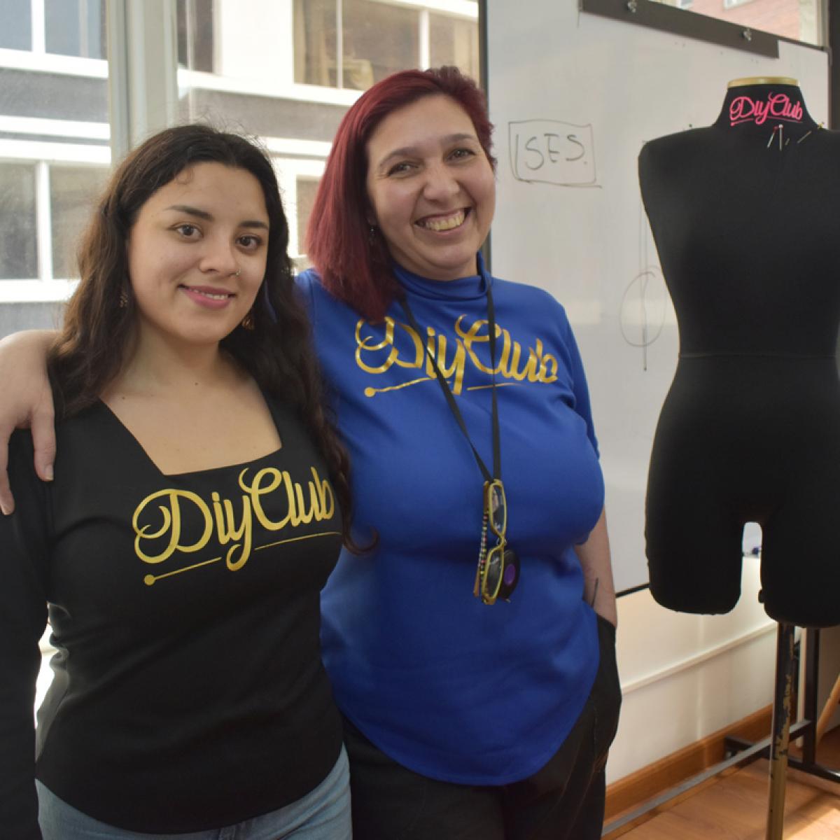 This pictures shows Laura and Dani standing in front of the camera with one arm around each other. They are both wearing shirts that read DIY Club. There is a pinnable mannequin next to them. 
