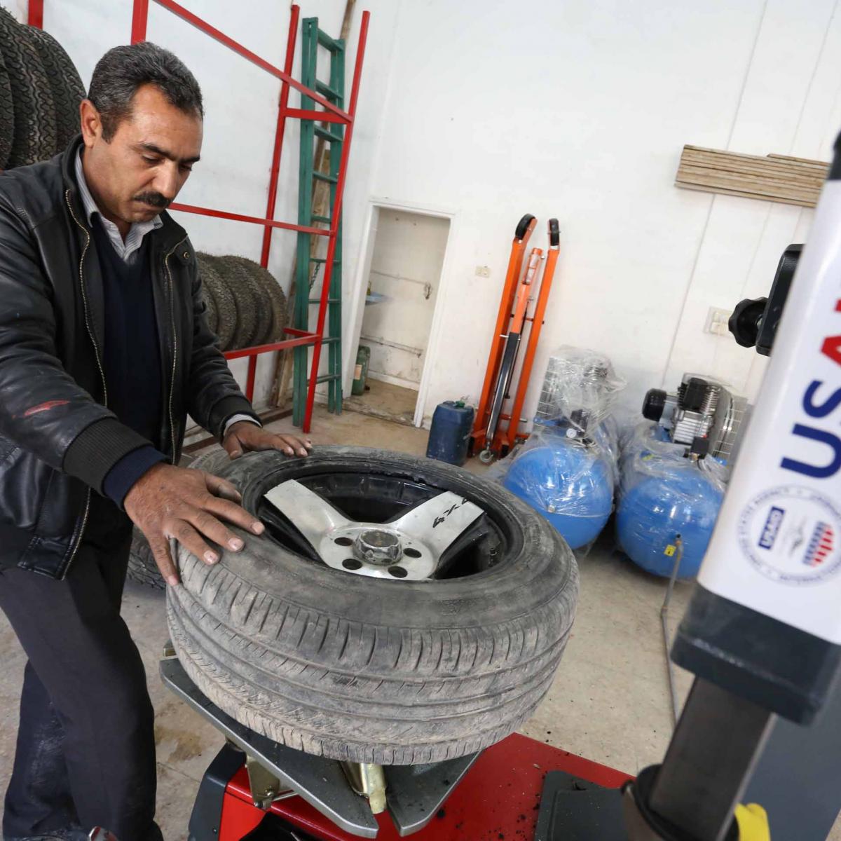 Abdullah Sharari, owner of a tire fixing station in Irbid, stands behind a tire changing machine in his new shop 