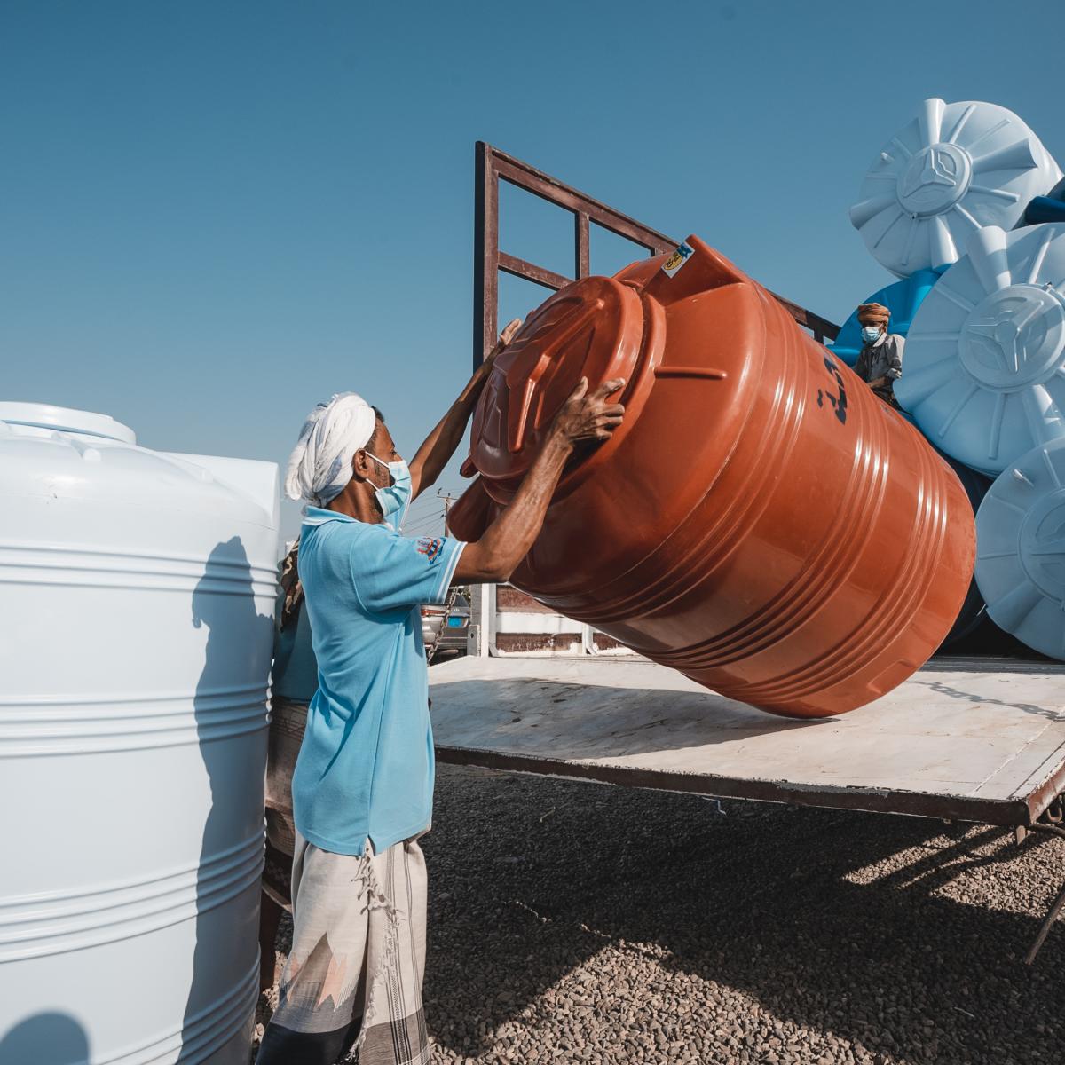 A worker lifts a plastic water tank at the USAID-supported Al Harmeen Factory in Lahij Governorate, Yemen.