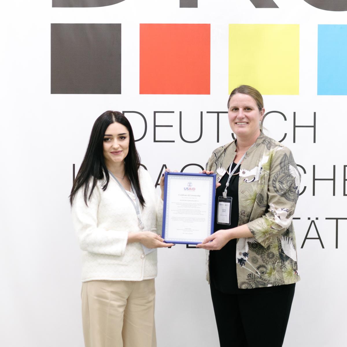 Manzura proudly receives a certificate from Laura Cizmo, USAID's Regional Economic Development Director 