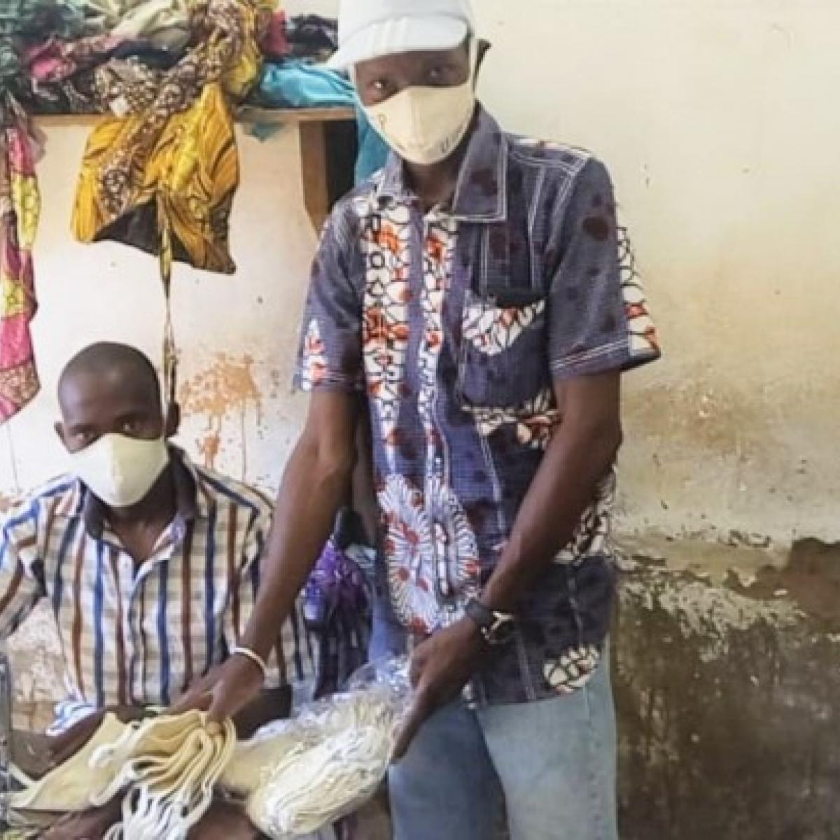 Baba Napo standing at a tailors’ shop collecting an order of face masks