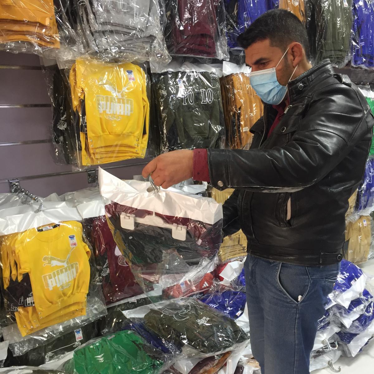 Khalaf Yousif selects different pieces to stock his new clothing shop in Khanki Camp in Duhok