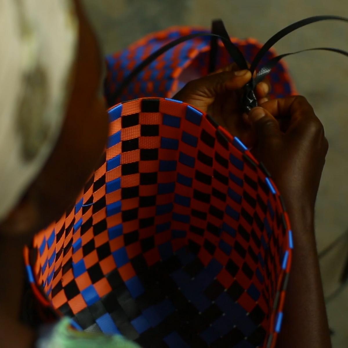 Closeup of woman weaving a colorful basket.