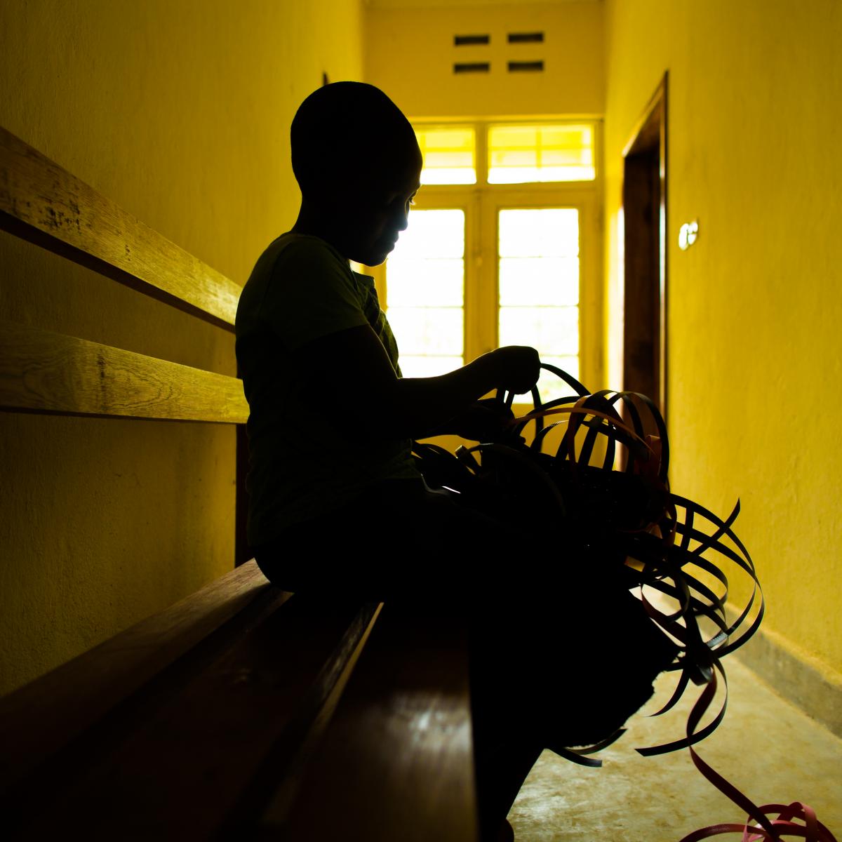 Silhouette of person weaving a basket.
