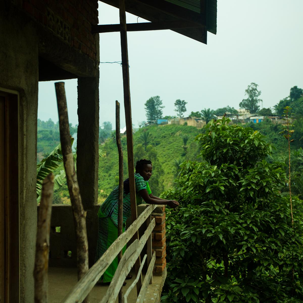 A woman leans on a wooden balcony.