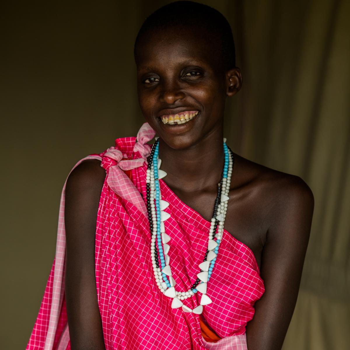 A portrait of a smiling Tanzanian woman in bright colored clothing.