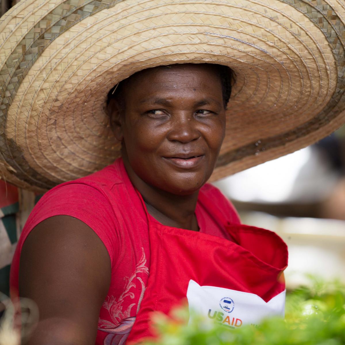 Christela, a vendor with the Kore Lavi voucher program, sells produce at her market stall