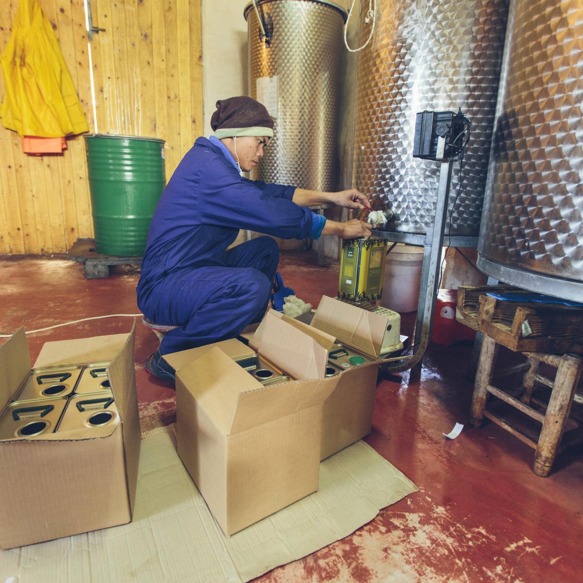 A worker fills containers with olive oil.