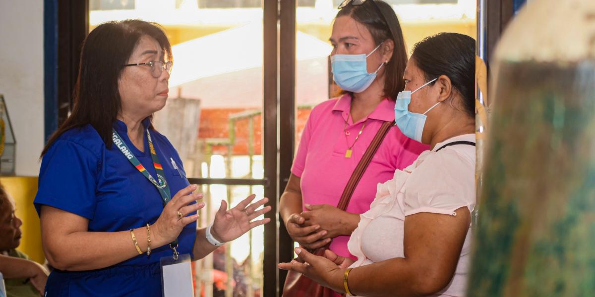 Karen is talking to two women in surgical masks who are family members of a person who uses drugs in the Philippines.