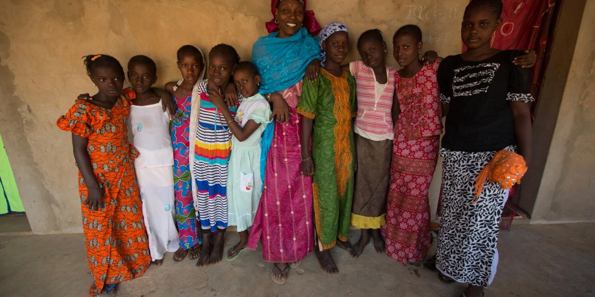 A woman surrounded by many children.