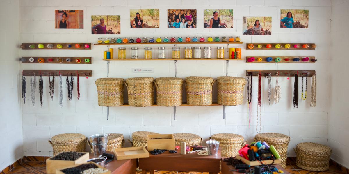 A display of baskets and other crafts alongside photos of the women who designed them.