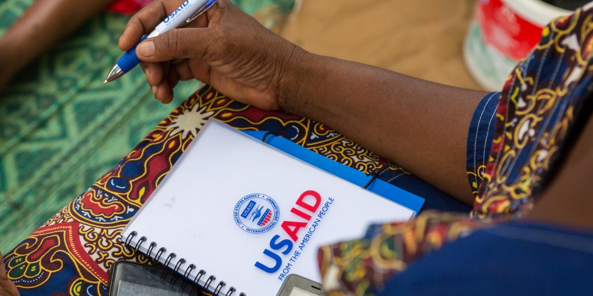 USAID-branded notebook held by a journalist.