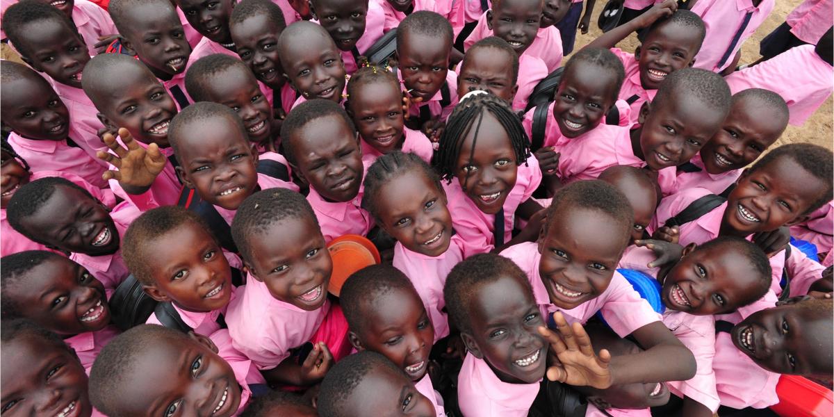 A group of young students dressed in pink look up at the camera