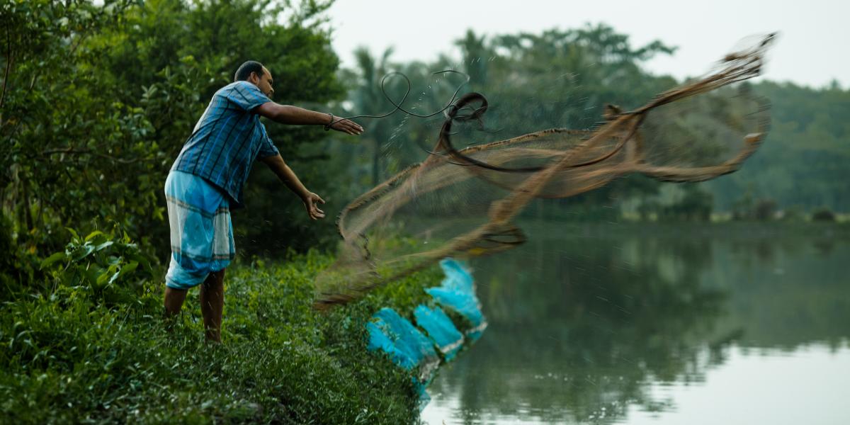 A man throwing a fishing net into a river.