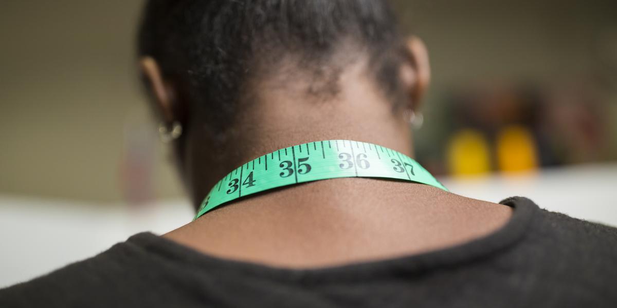 A measuring tape draped around the back of a woman's neck.