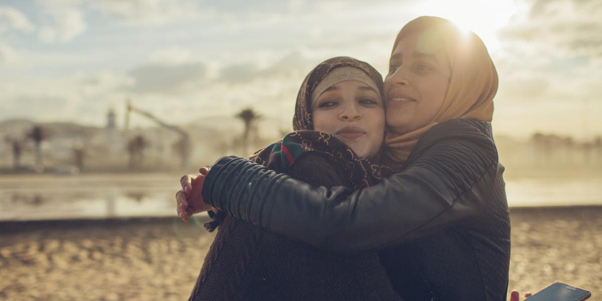 The two sisters hug each other on a beach in Northern Morocco.
