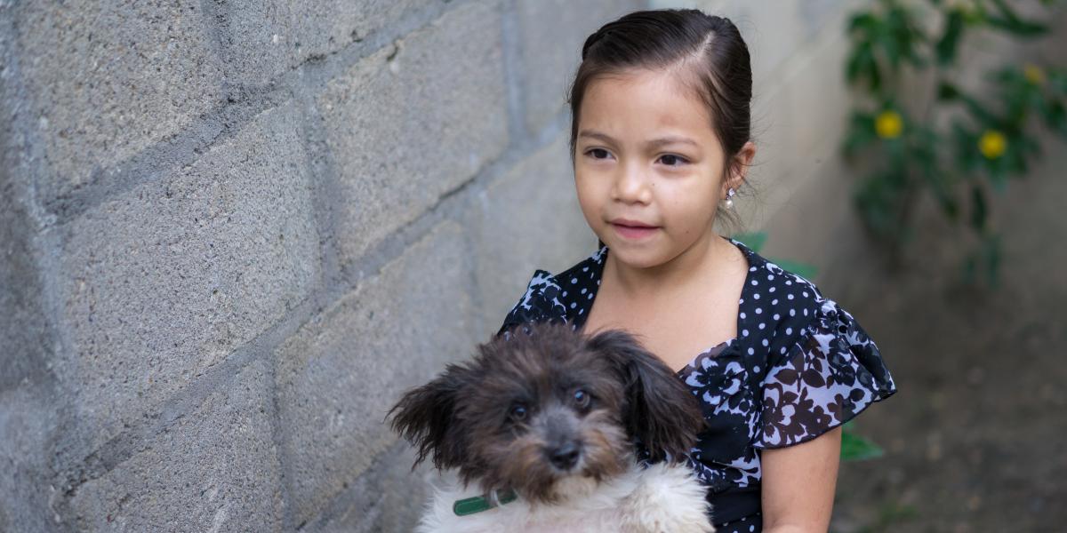A young girl carrying a puppy.