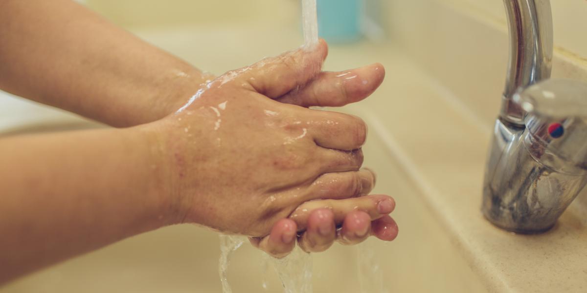 Closeup of hands being washed under a faucet